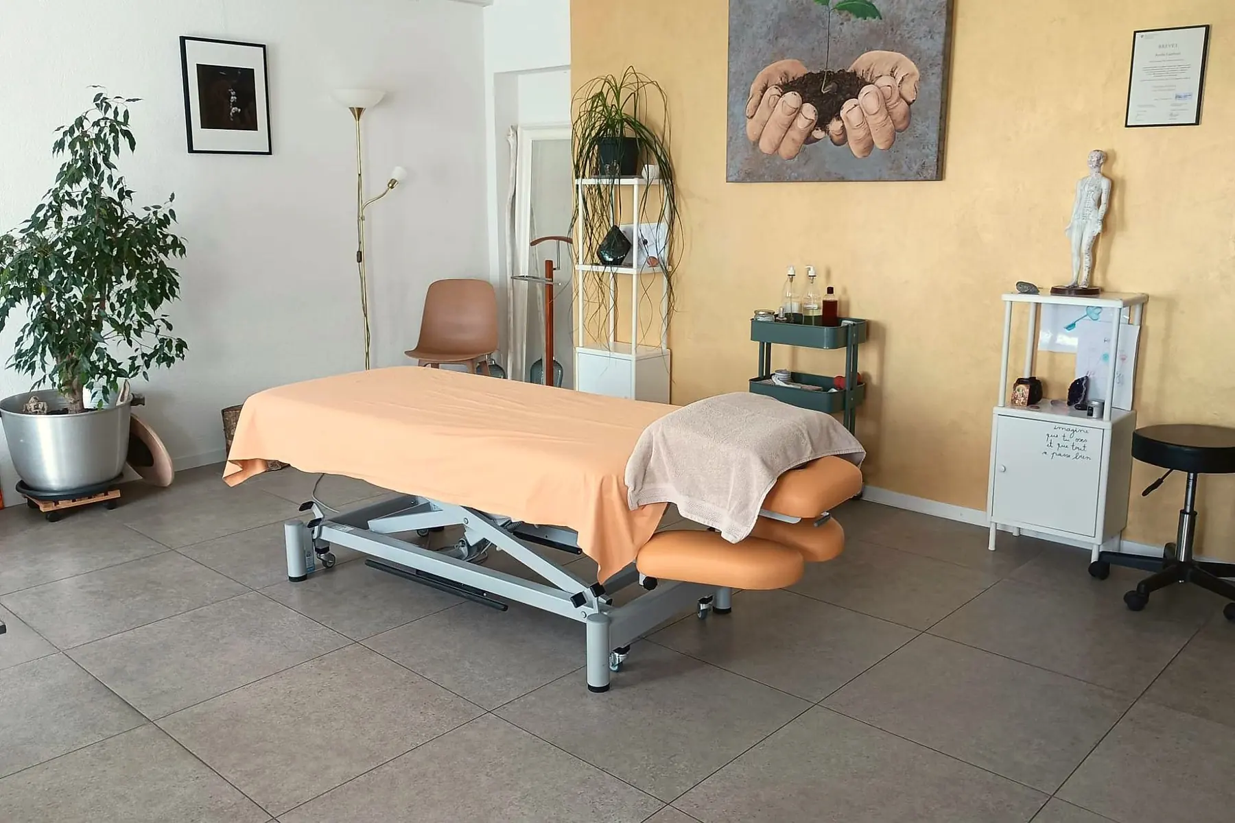 Le cabinet d’Aurélie à Coffrane : table de massage, mur doré et plantes