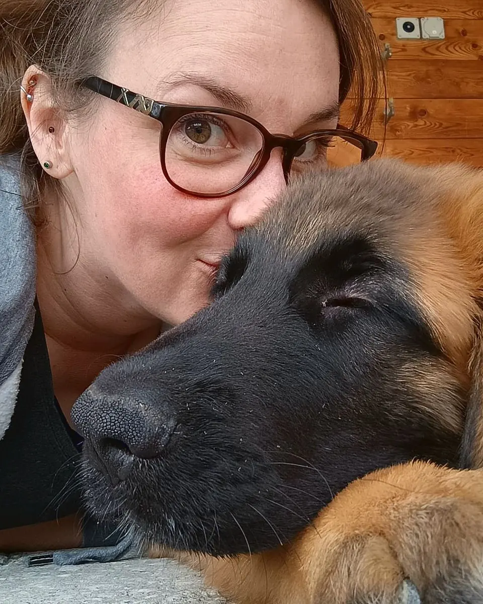 Aurélie embrassant la tête de son chien, un jeune léonberg